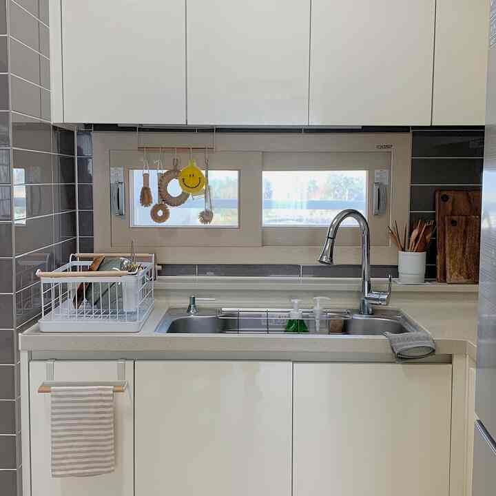Bright white and natural wood-toned kitchen sink area featuring cutting boards and kitchen towel with a clean, cozy ambiance