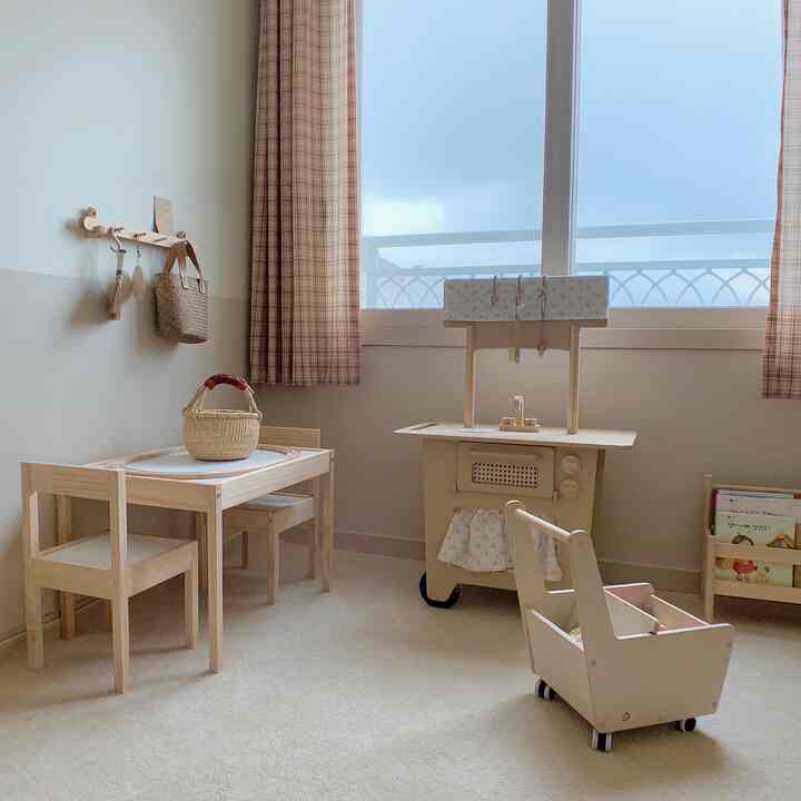 Light beige natural-toned kids' room featuring wooden kids' desk set and check curtains with a warm, cozy atmosphere