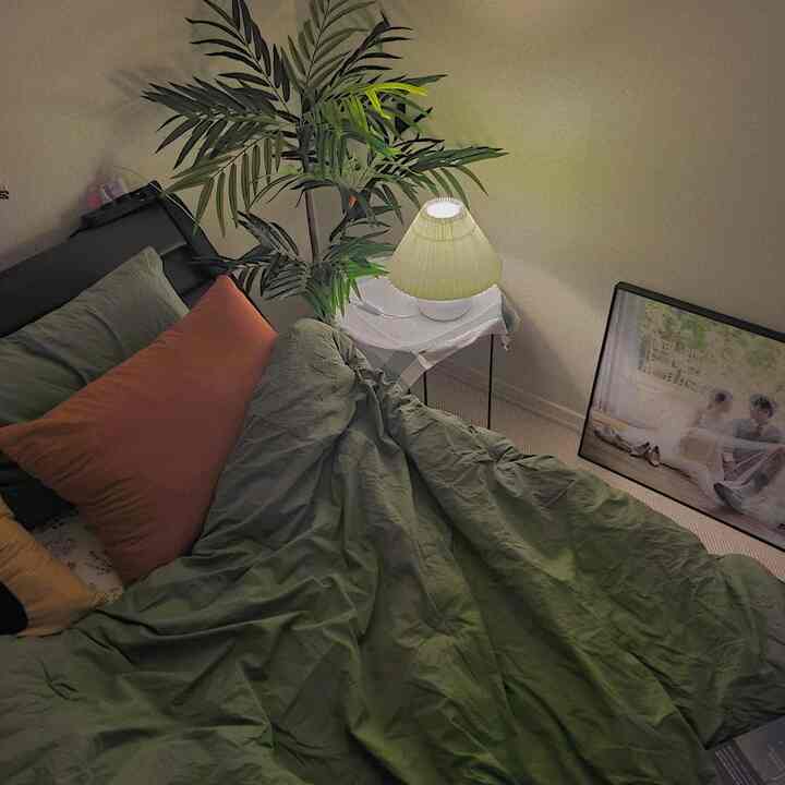 Cozy Nordic-style couple bedroom featuring green bedding and an artificial tree