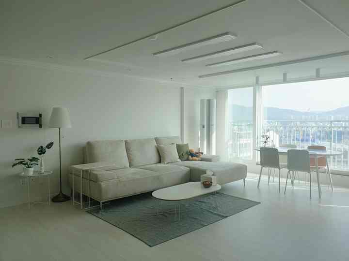 Bright living room in white and beige tones featuring a beige sofa and dining table with a natural atmosphere