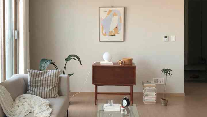 明るい白色の壁に木製コンソールテーブル、ソファ、植物、絵画が調和したリビングのインテリア