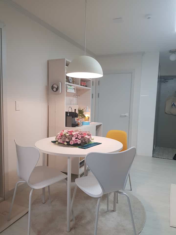 Light white and beige toned small dining room featuring a round table with three chairs in a neat layout