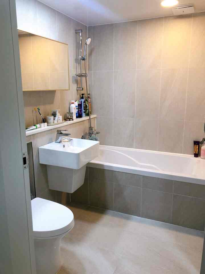Beige-tone porcelain tiled bathroom featuring a bathtub and sleek flap-style mirrored vanity, presenting a clean and luxurious space