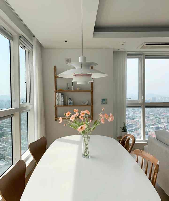 白と木目調が調和するダイニング、ペンダントライトと花瓶が配置された明るく自然な雰囲気のインテリア