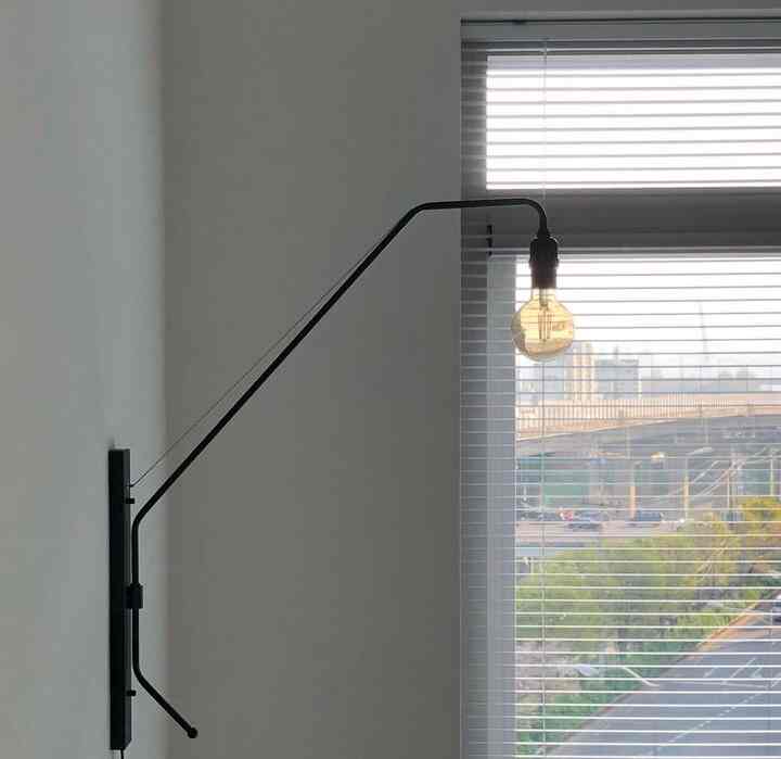 White-toned entrance featuring blinds and a wall sconce with a clean and modern interior atmosphere