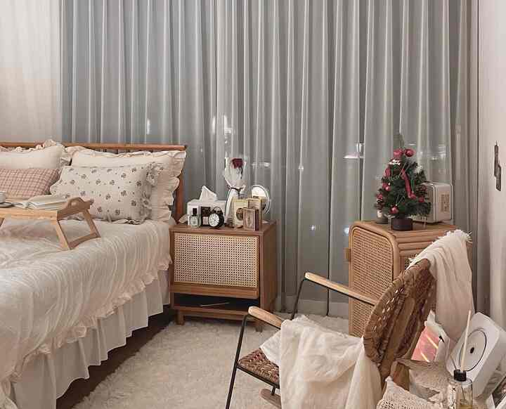 Natural-tone bedroom featuring rattan furniture, frilled bedding, and a mini Christmas tree creating a cozy atmosphere