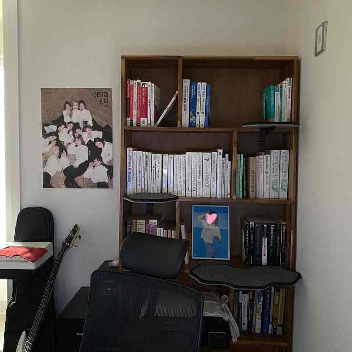 黒と濃いブラウンの木目調が特徴のホームオフィス空間、本棚とキャットキックが配置されたヴィンテージ感のある作業室