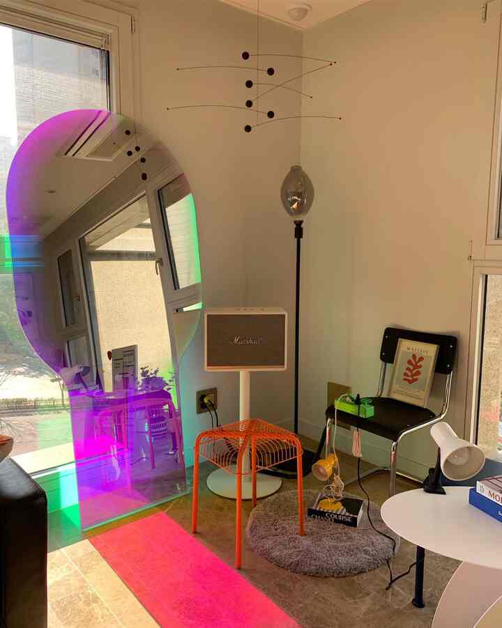 Warm-toned living room featuring a large colorful mirror and retro-style furniture in a cozy home cafe setting