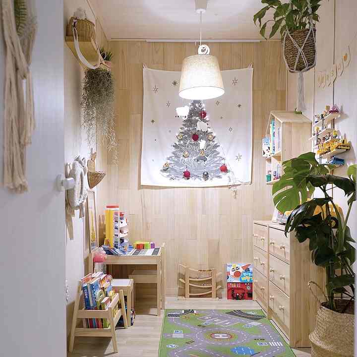 Natural wood tones and white color blend in a baby’s kids' room featuring a fabric Christmas tree on the central wall with a warm atmosphere