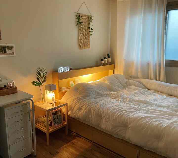 ナチュラルな木目調と白色が調和した、ベッドとナイトテーブルが配置された居心地の良い寝室