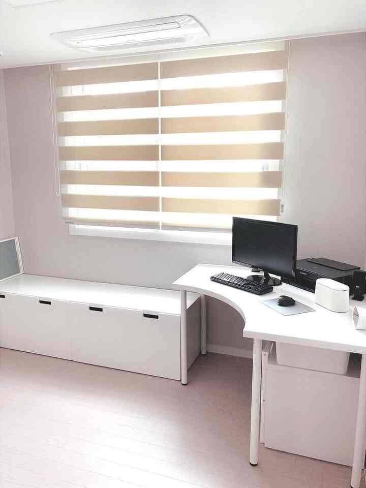 White-toned home office featuring a corner desk and clean storage boxes in a modern, compact room