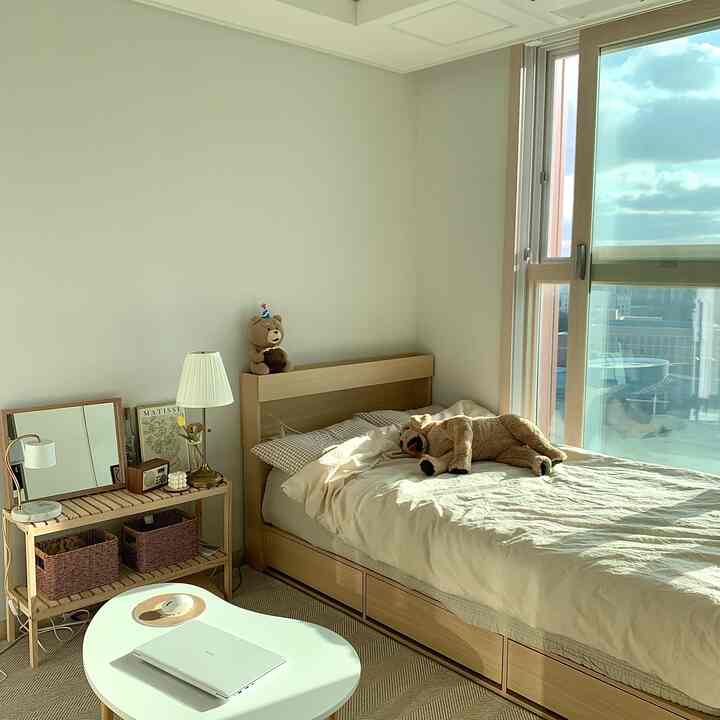 Natural wood tones and beige rug in a studio bedroom featuring a low bed and small table creating a cozy atmosphere