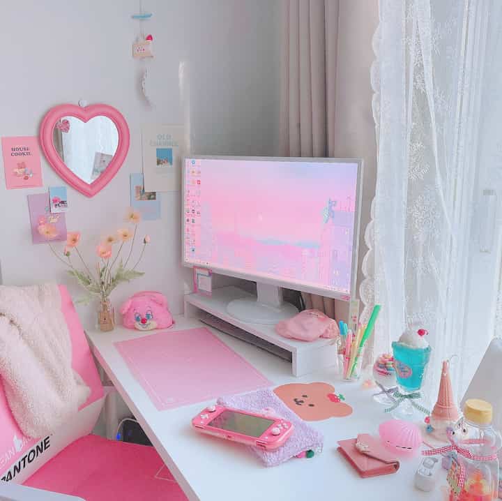 Pastel pink and white-toned single household home office featuring a pink desk chair and heart-shaped mirror with cozy decor