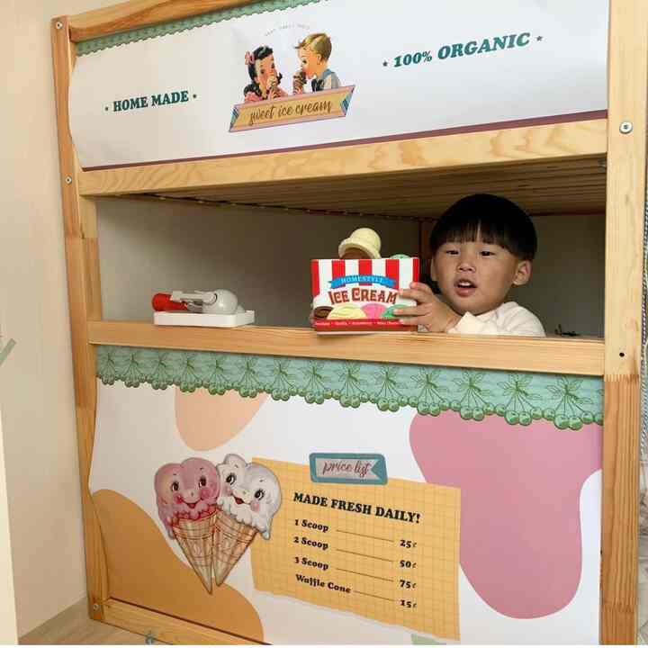 明るい木目調の子供部屋、パステルカラーの装飾と遊び用の木製構造物で遊ぶ子供がいる雰囲気のあるインテリア