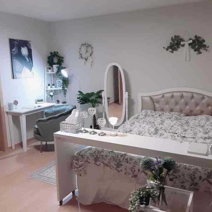 ホワイトとナチュラルトーンの寝室、フルレングスミラーと植物が配置されたシンプルで雰囲気のあるインテリア