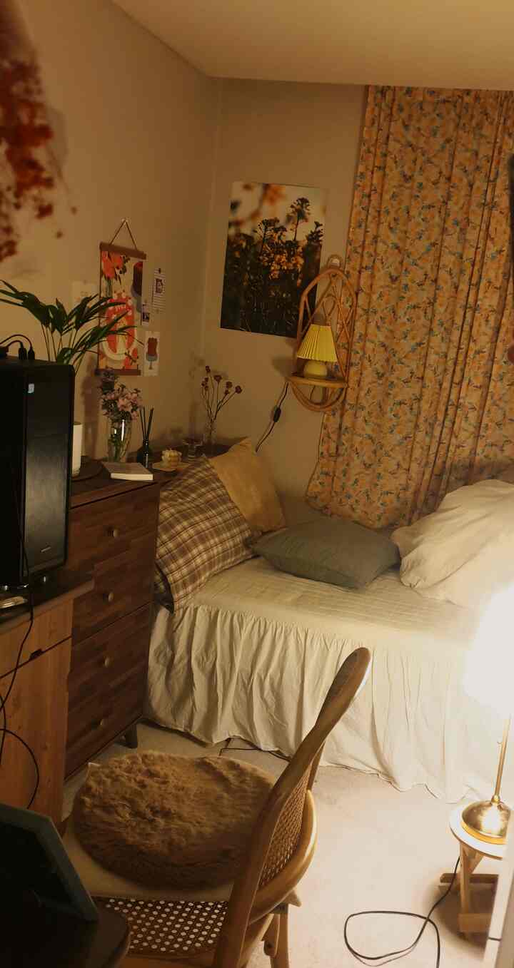 Cozy small bedroom in warm wood tones and beige hues featuring a bed, chair, and wall art to create a relaxed atmosphere