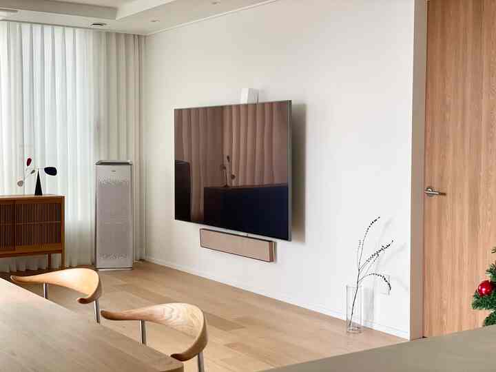 White and wood tone living and dining room featuring Carl Hansen CH88 dining chairs and wall-mounted TV in a modern setting