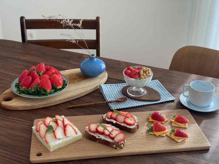 Natural-toned kitchen space featuring a walnut table with oak cutting boards and plated strawberries, creating a cozy atmosphere