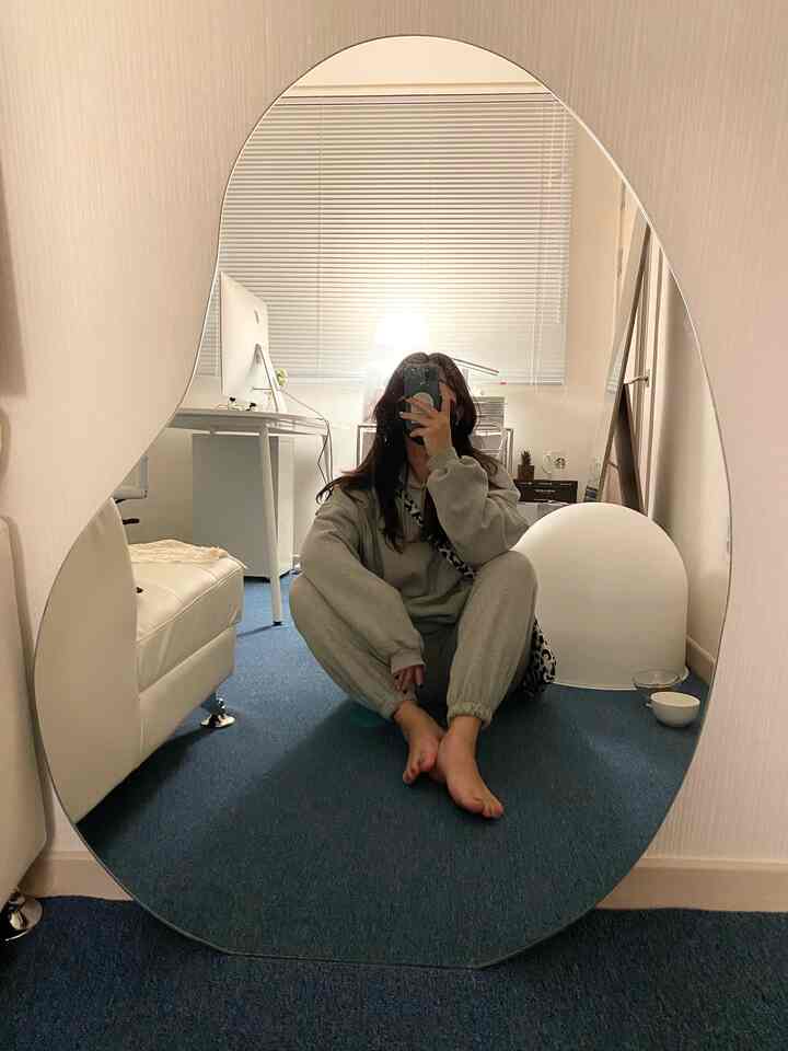 Blue carpet and white furniture in a studio workspace featuring a large rounded mirror and simple modern design