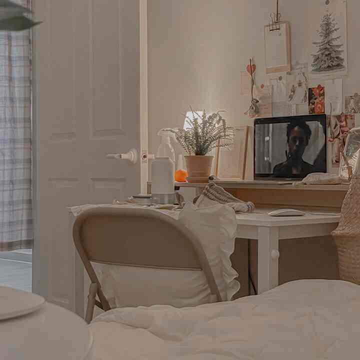 Warm beige and ivory toned single household room featuring a desk, cushion, and curtain with cozy vintage ambiance
