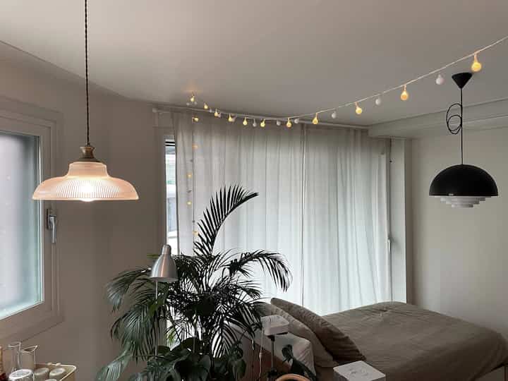 White and natural tone living room with glass shade and black pendant lights along with string lights adding cozy atmosphere
