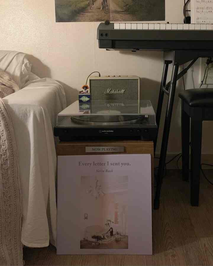 ホワイトとウッドトーンが調和したリビングの一角に、ターンテーブルとスピーカー、LP収納キャビネットが配置された雰囲気のあるインテリア