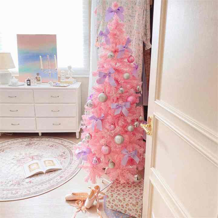 ピンクとホワイトのトーンのウォークインクローゼット、ピンクのクリスマスツリーと白いチェストが配置された雰囲気のあるインテリア