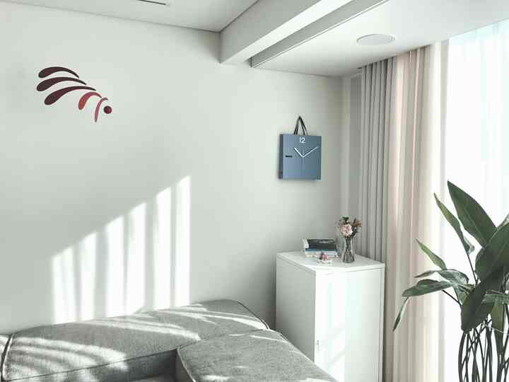 White and gray toned living room featuring a paper bag clock and greenery creating a bright, clean atmosphere