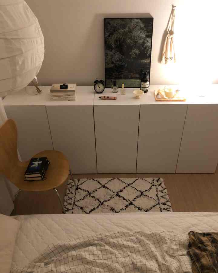 White and brown toned bedroom featuring white cabinets, wooden chair, and cozy ambient lighting in a minimalistic setting