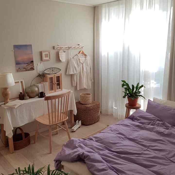 温かみのある木目調と白いカーテンが調和した、ラベンダー色の寝具が映える落ち着いた寝室のインテリア