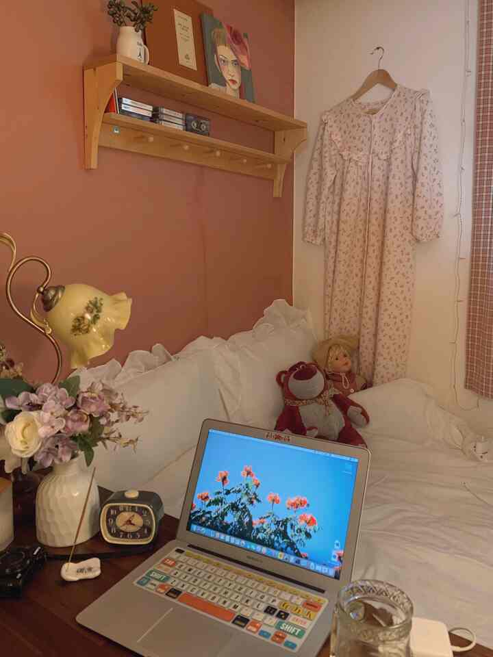 Cozy bedroom in warm brown and white tones featuring bed with white bedding, wall-mounted shelf, and floral pajama hung on wall
