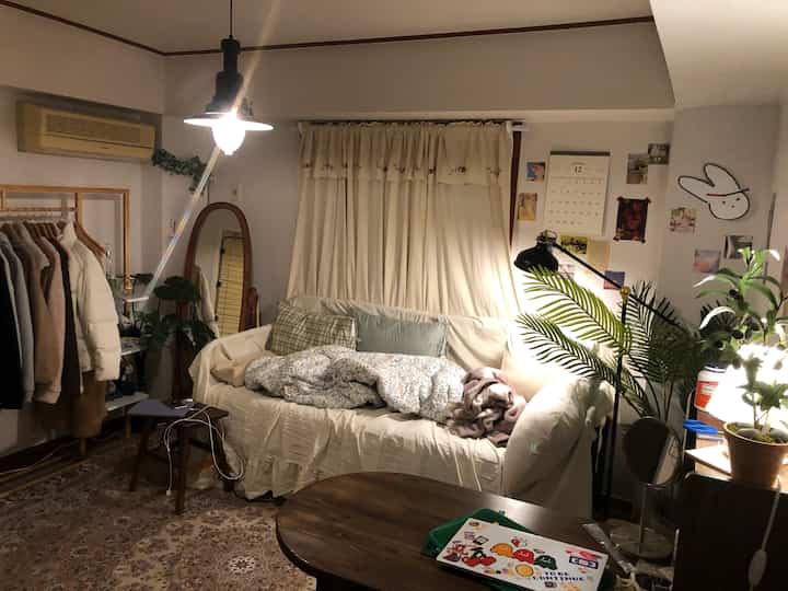 Ivory and wood-tone studio living room featuring a large sofa, wooden furniture, and cozy plants