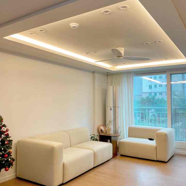 Bright white and natural wood tone living room featuring a modular sofa and Christmas tree creating a cozy atmosphere