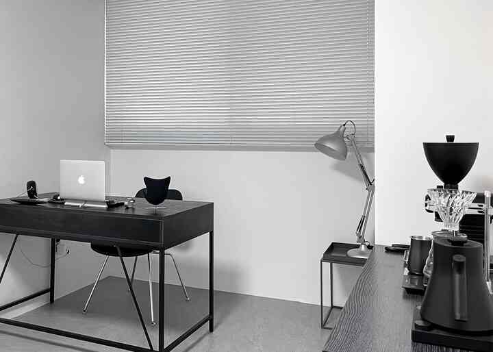 Monotone and silver-toned home office space featuring a simple desk and lamp with a minimalistic vibe