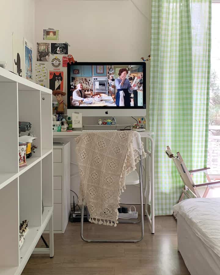White-toned compact single household room featuring a centrally placed desk with computer setup as home office