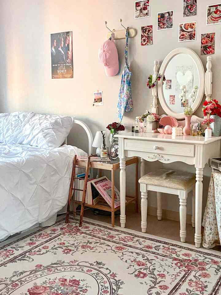 A cozy bedroom in white and pink floral tones featuring a vintage-style rug and classic dressing table with mirror