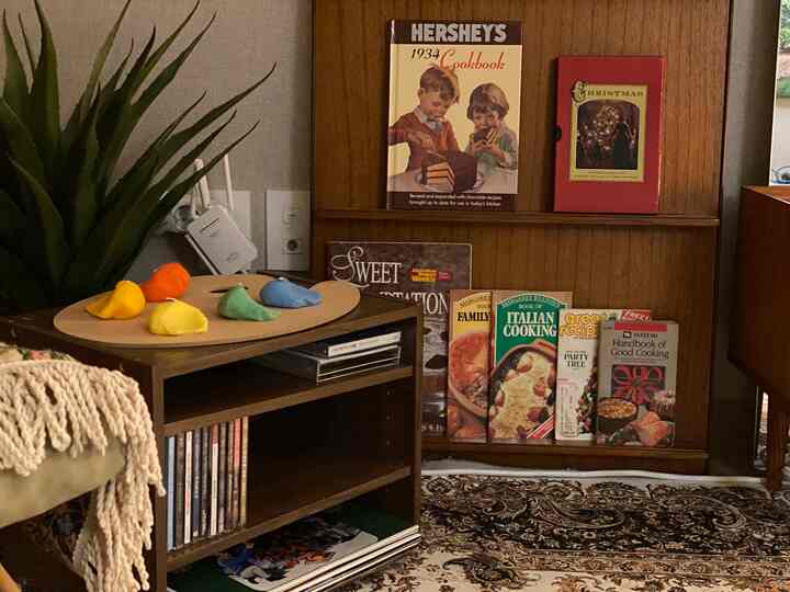 暖かいブラウンの色調のリビングの一角、ヴィンテージ料理本とレコード収納キャビネットが配置された雰囲気のあるインテリア