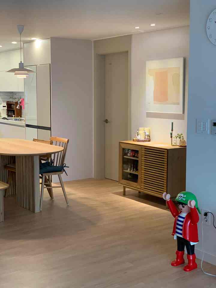 White and wood-toned, simple modern dining room with two-person dining table and storage cabinet in a newlywed home