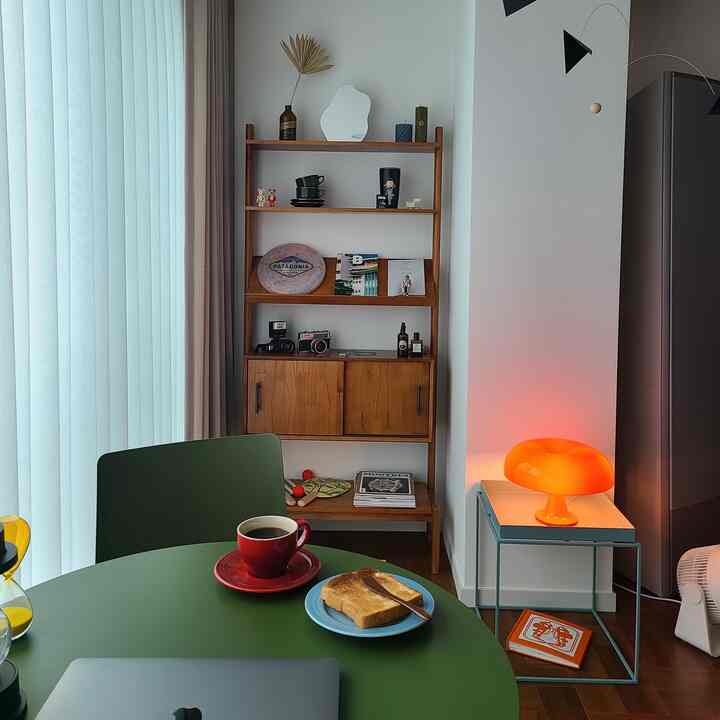 Natural wood tone and olive green table in a veranda space with orange lighting and cozy home cafe setup
