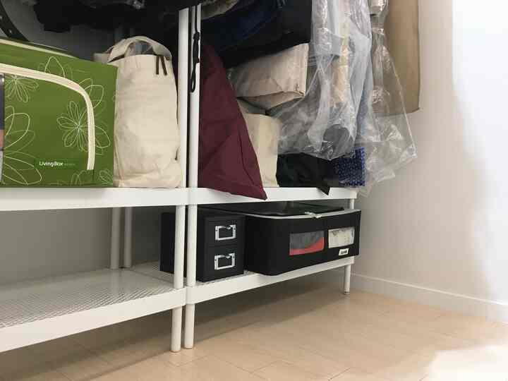 White-toned walk-in closet space featuring assorted storage boxes and neatly arranged clothes in a compact room