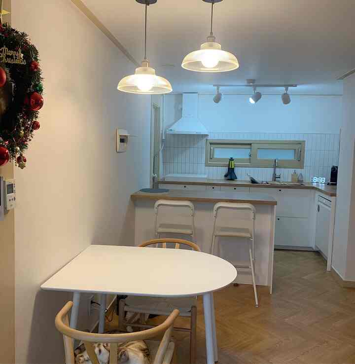 White and wood tone kitchen and dining area featuring pendant lights, displaying a clean and cozy atmosphere
