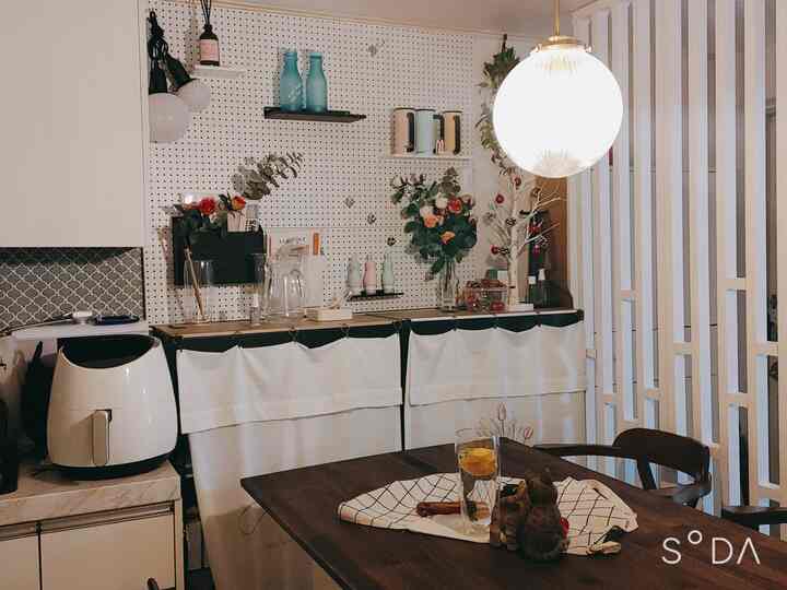 White and natural toned kitchen featuring pegboard wall, room divider, decorative flowers, and glass pitcher in cozy atmosphere