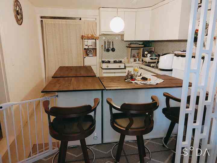 White and wood tone D-shaped kitchen featuring a wooden island table and cabinets, creating a cozy atmosphere