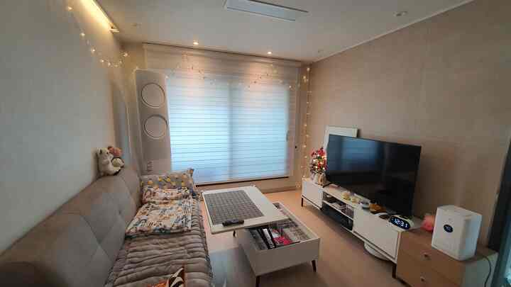Beige and white toned living room featuring neat sofa, coffee table, and TV stand with cozy atmosphere