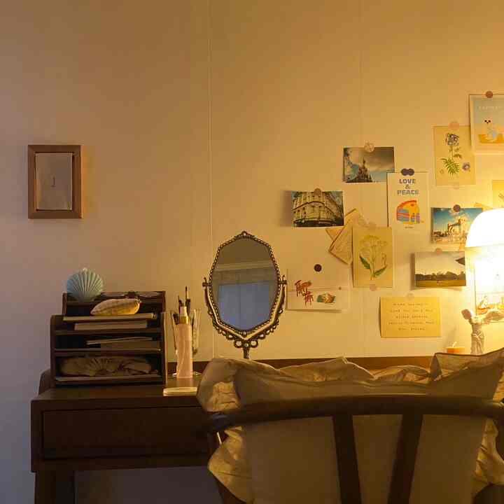 暖かいイエローの照明が印象的なフレンチカントリー風のデスクと壁に飾られたアートポスターのある居心地の良い空間