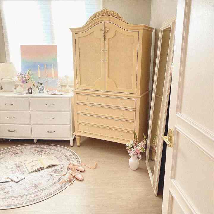 A cozy bedroom with beige and yellow-toned wardrobe, featuring a floral rug and full-length mirror, showcasing classic style interior
