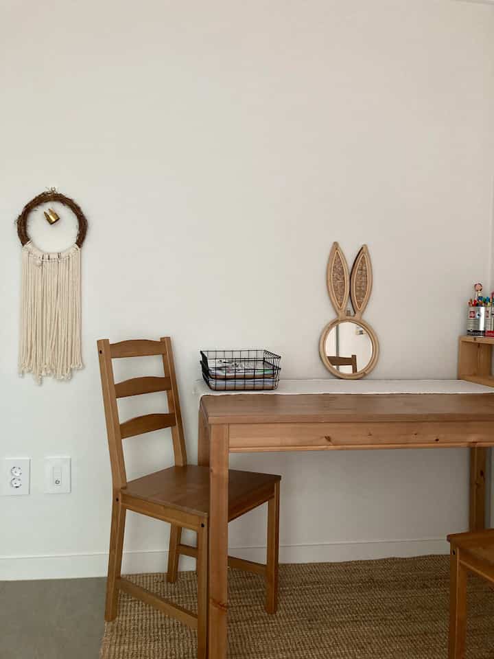 白い壁と木目調のデスクが配置された子供部屋、マクラメ装飾が雰囲気のある空間を演出