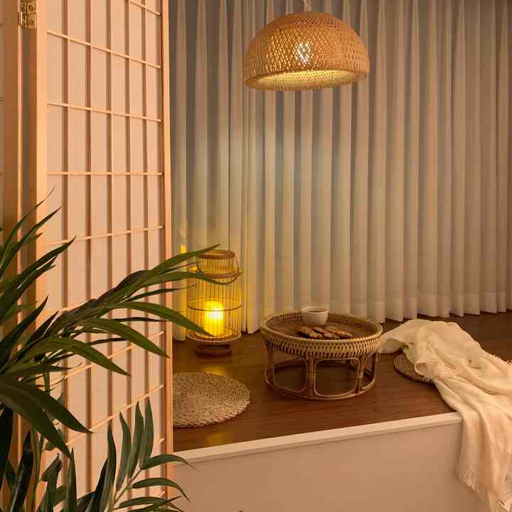Cozy natural living room in warm white and wood tones featuring rattan table, pendant light, and room divider