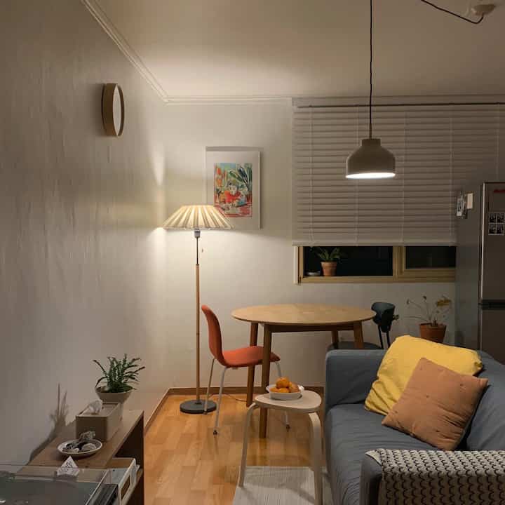 Compact living room with natural wood tones and a blue sofa, featuring a round table and warm lighting