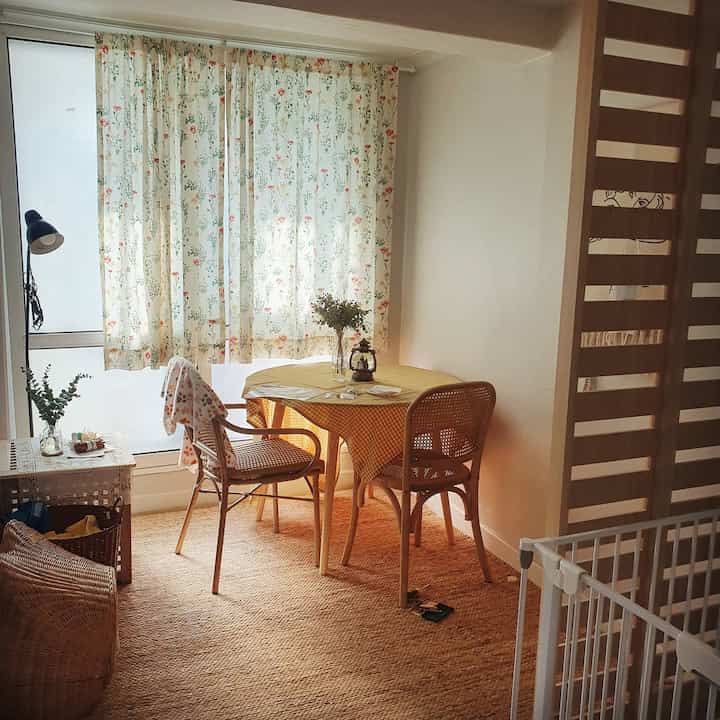 Yellow-toned small dining space featuring wood furniture and floral curtains with a warm cafe-style ambiance